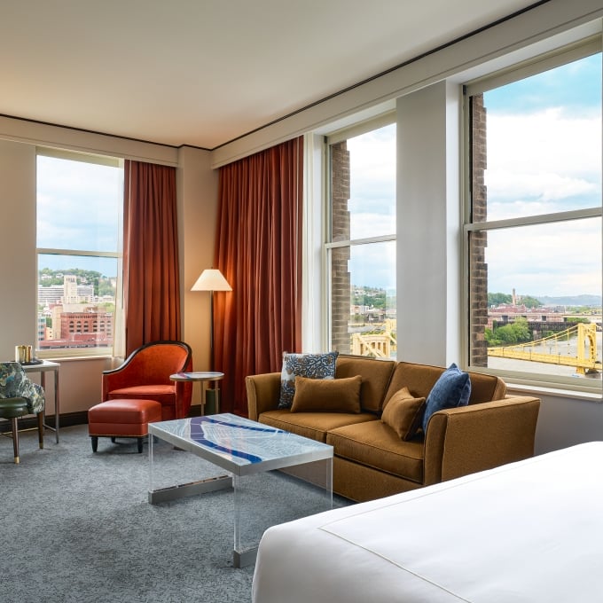 Junior Suite featuring a king bed, a tan sofa, an acrylic coffee table, and large windows with bridge views.