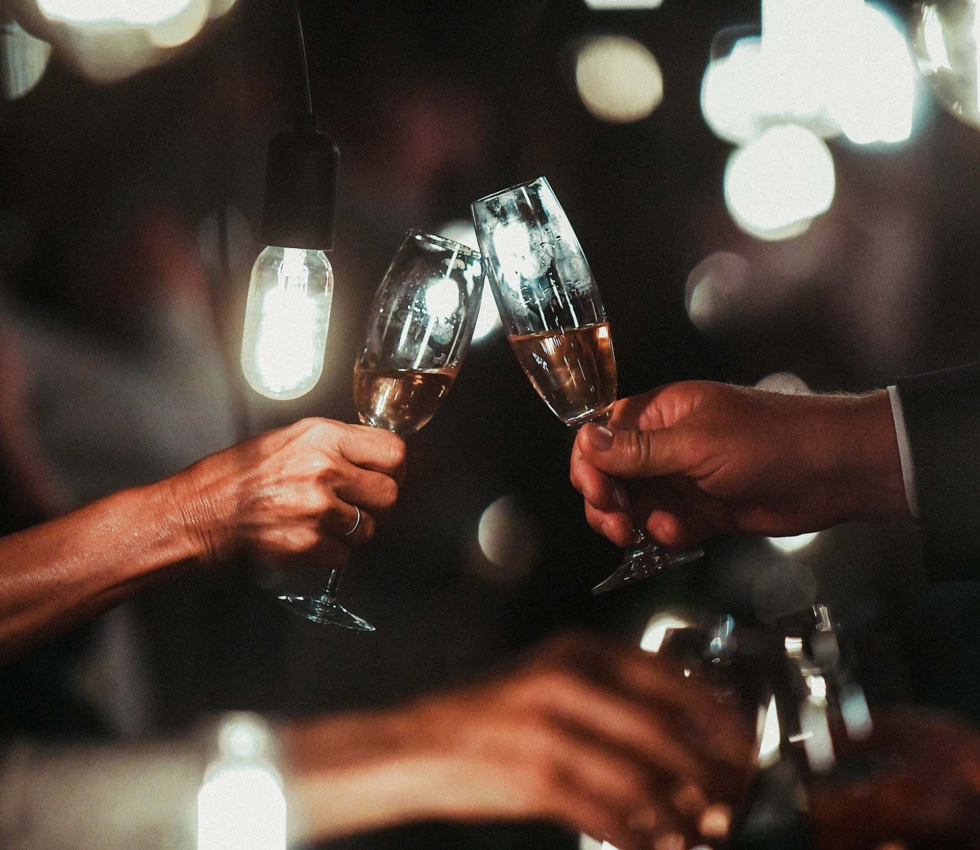 Champagne flute toast with hanging bulbs in a dark room