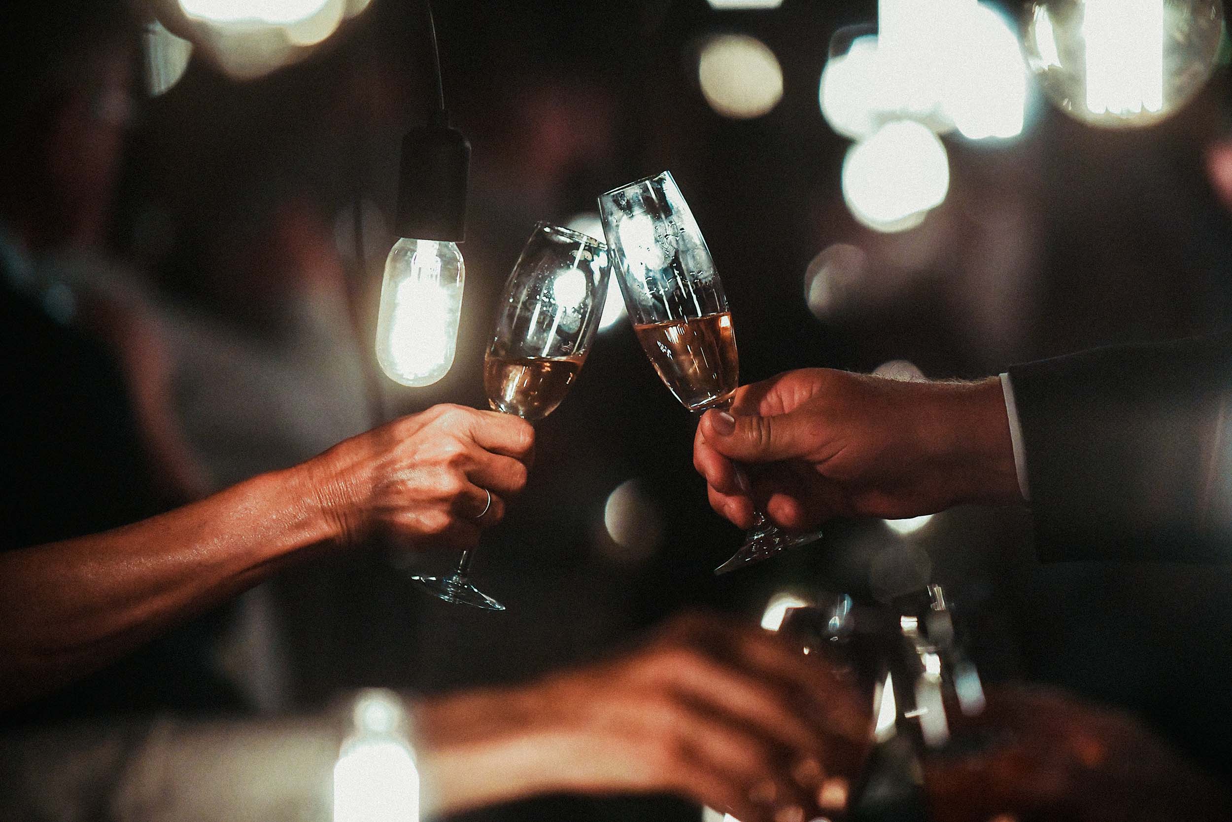Champagne flute toast with hanging bulbs in a dark room