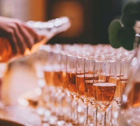 Rows of champagne flutes being filled at an event