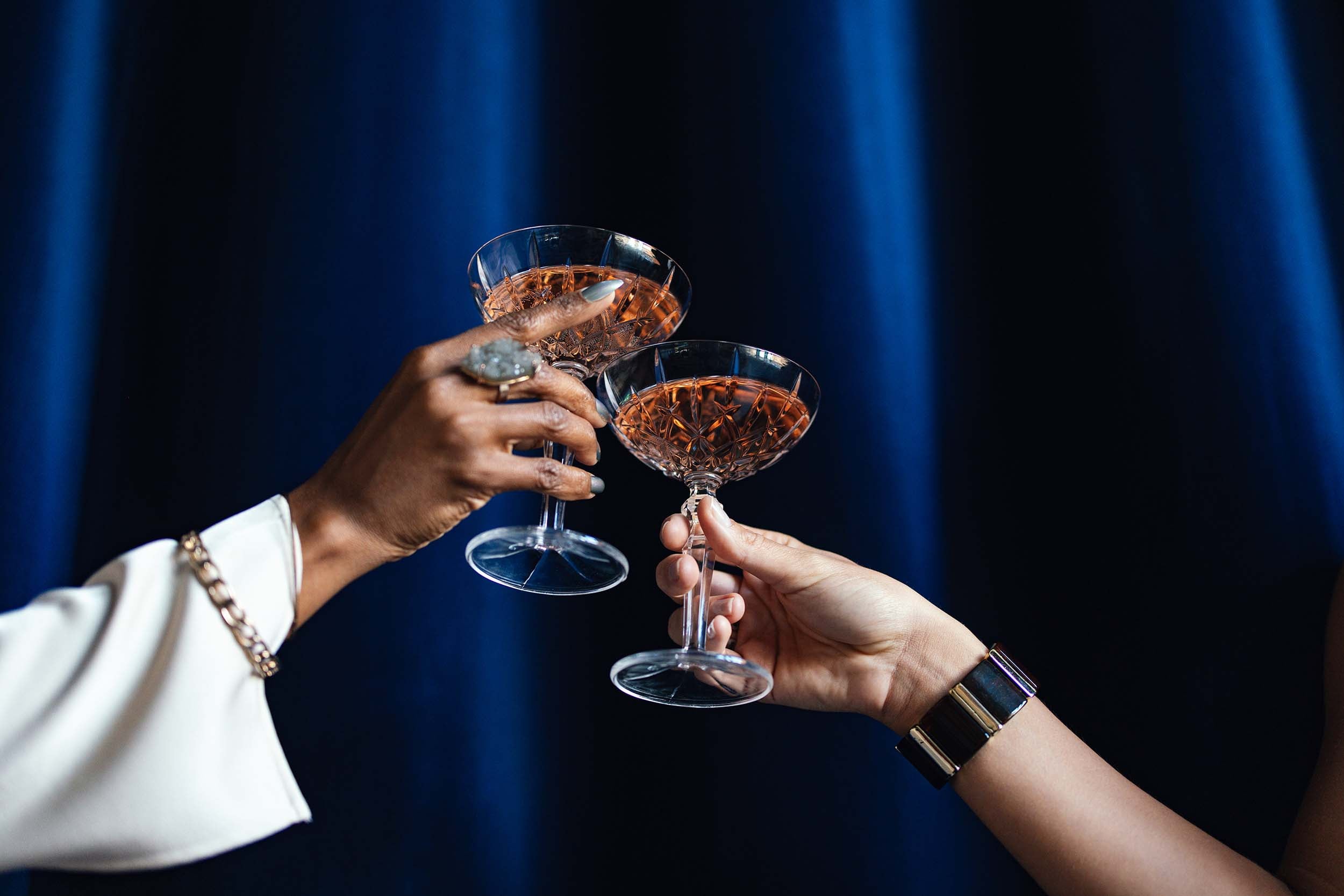 Two glasses cheers in front of blue curtain