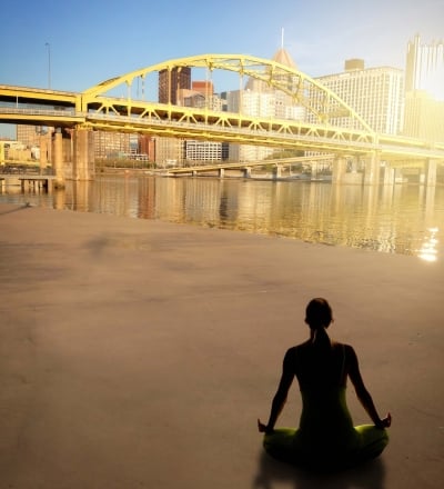 A woman meditating on a beach with a city view