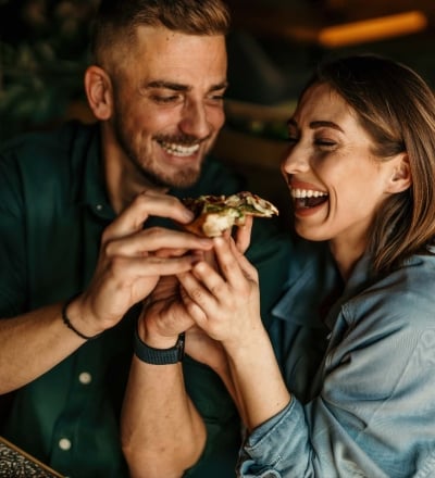 A couple sharing pizza and laughing