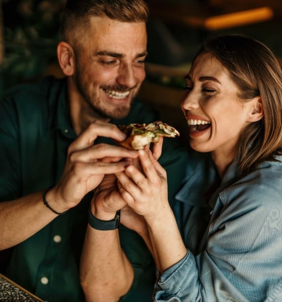 A couple sharing pizza and laughing