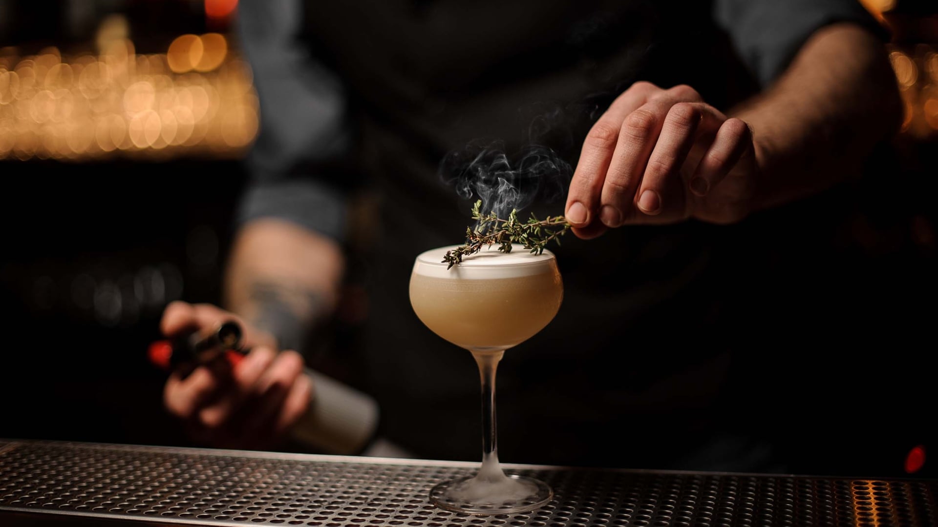 A bartender placing the garnish on a cocktail