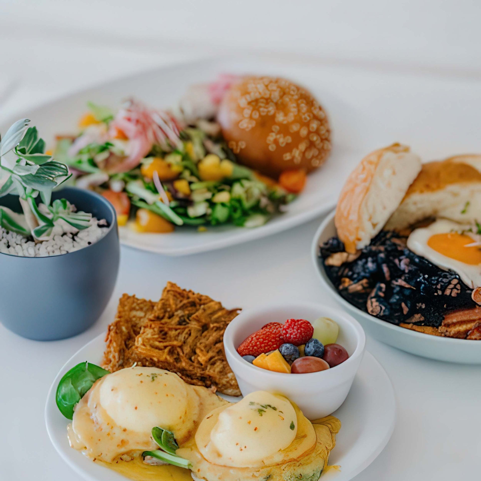 A variety of breakfast dishes sit on a white table cloth