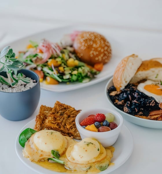 A variety of breakfast dishes sit on a white table cloth