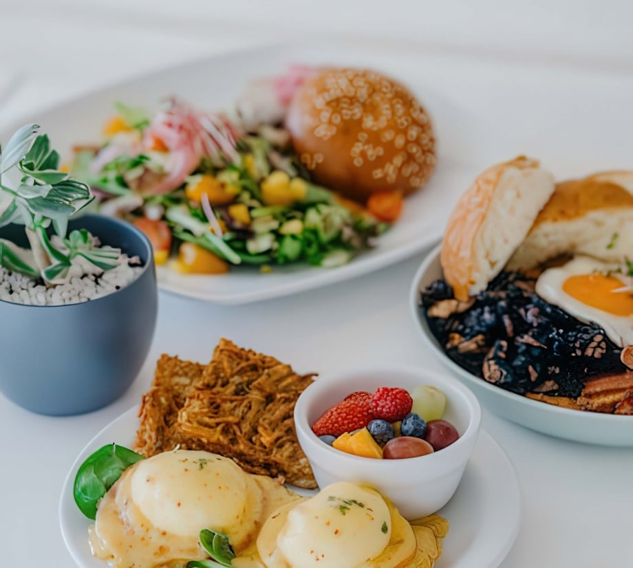 A variety of breakfast dishes sit on a white table cloth