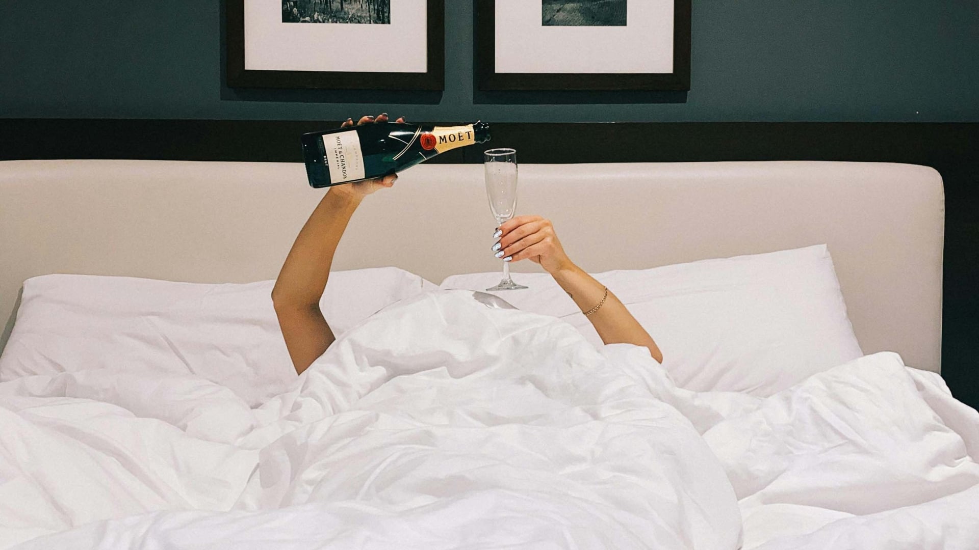 A woman pouring champagne in a King bed