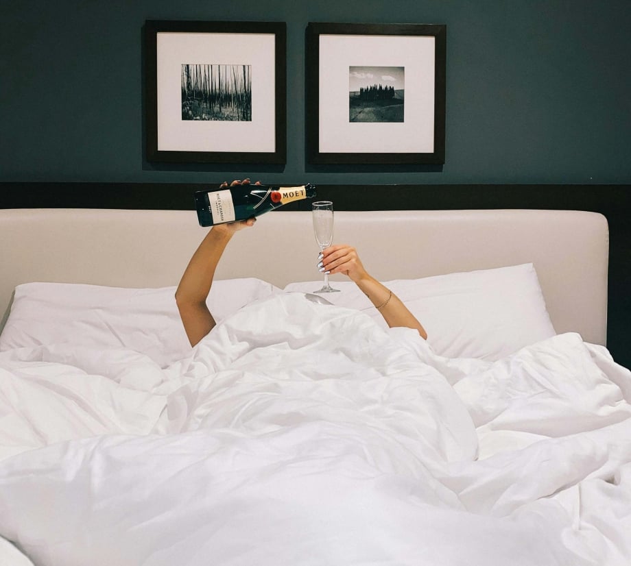 A woman pouring champagne in a King bed