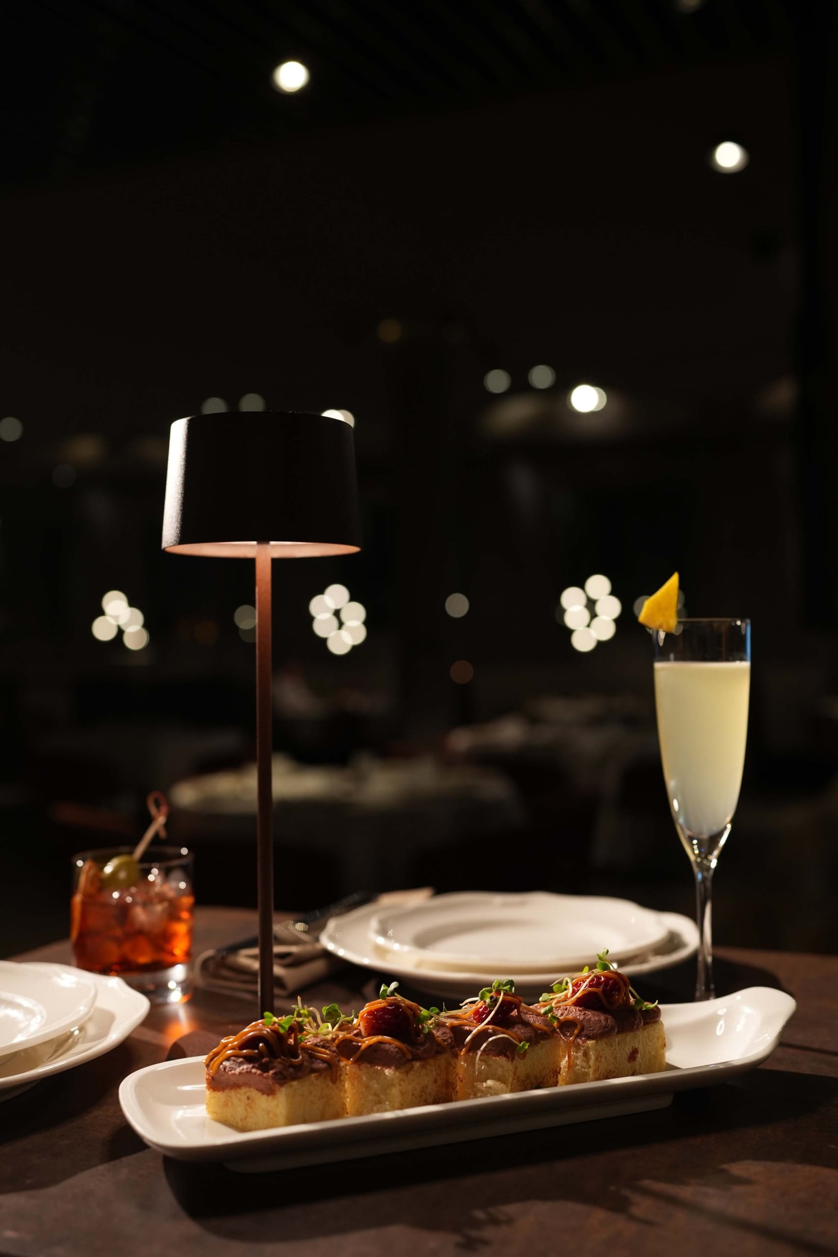 A dish and cocktail sit on a wooden table