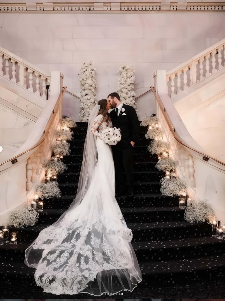 A bride and groom kiss standing on a decorated staircase