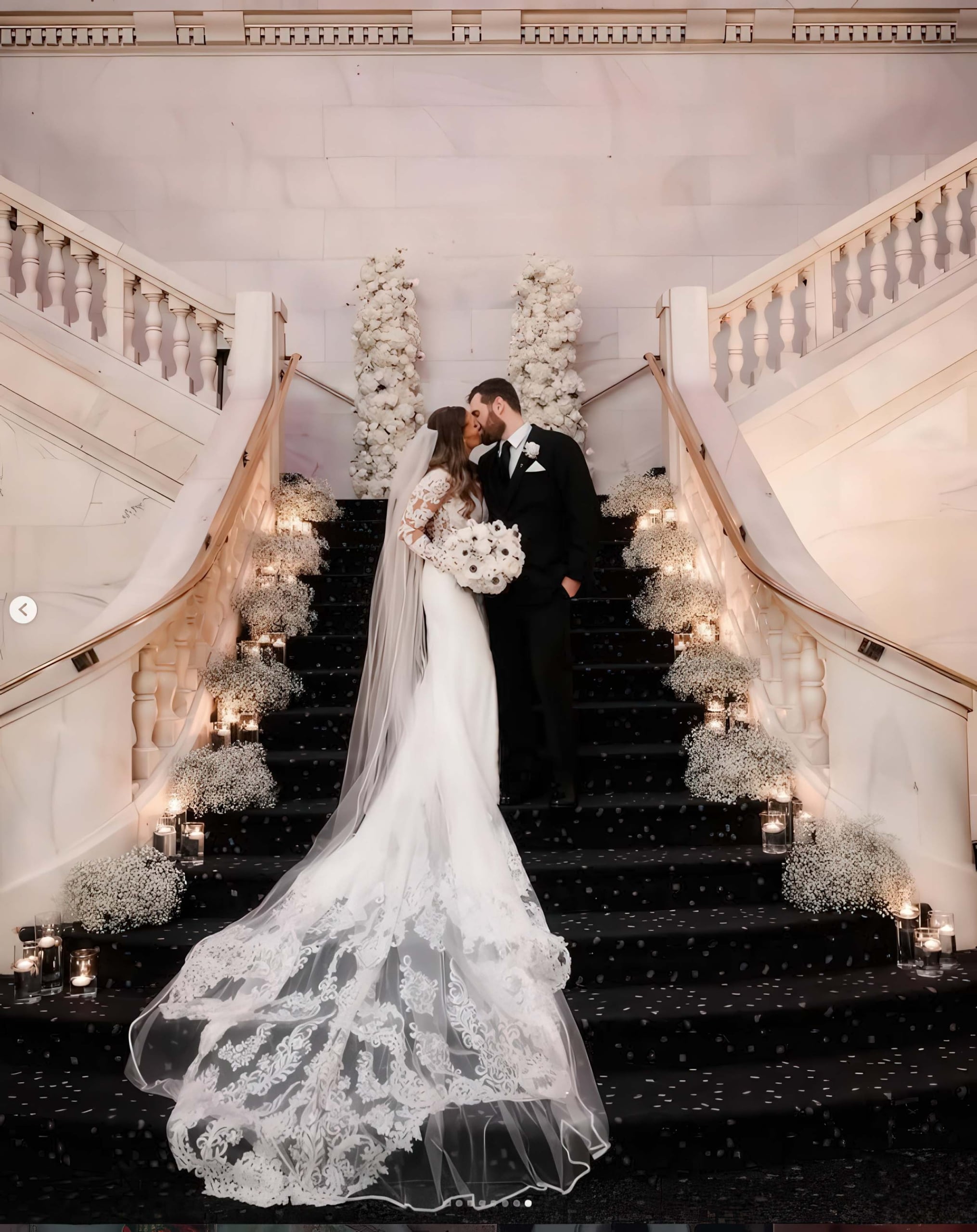 A bride and groom kiss standing on a decorated staircase