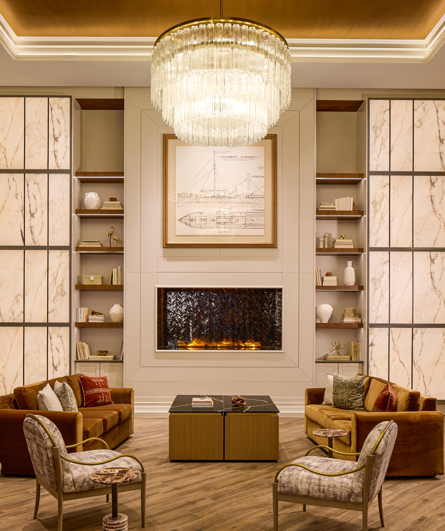 Luxurious hotel lobby lounge featuring a large crystal chandelier, velvet sofas, and an elegant fireplace.