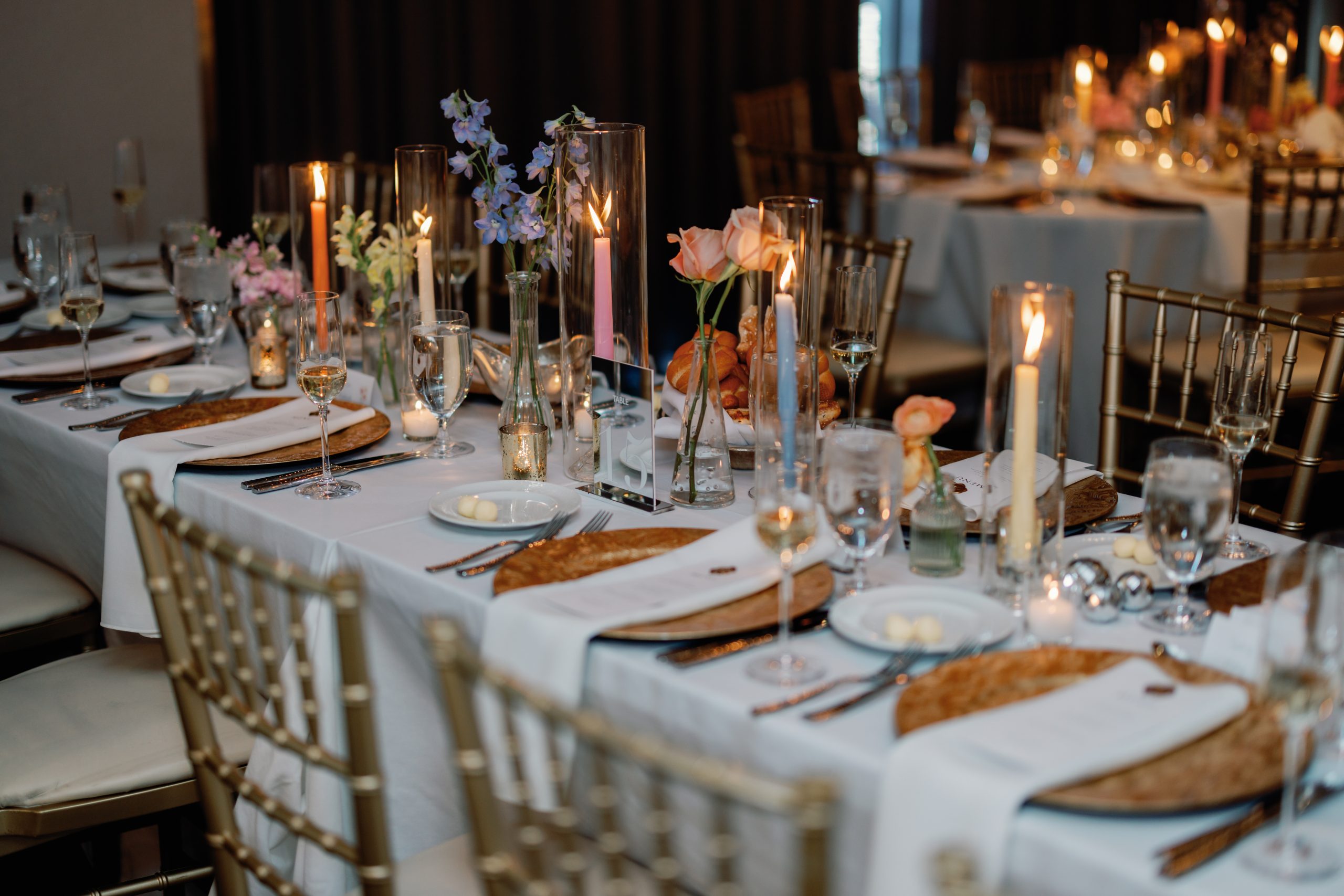 Elegant banquet table set for a formal dinner with candles, glassware, and floral centerpieces.