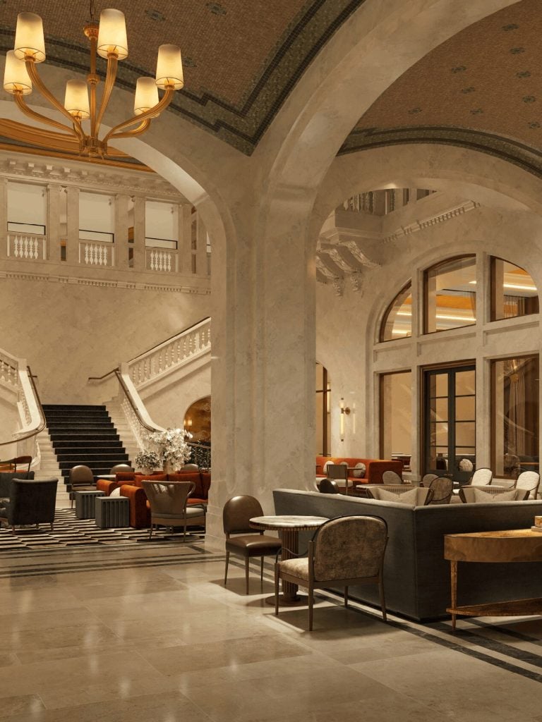 Elegant hotel lobby with arched walls, marble staircase, and warm chandeliers